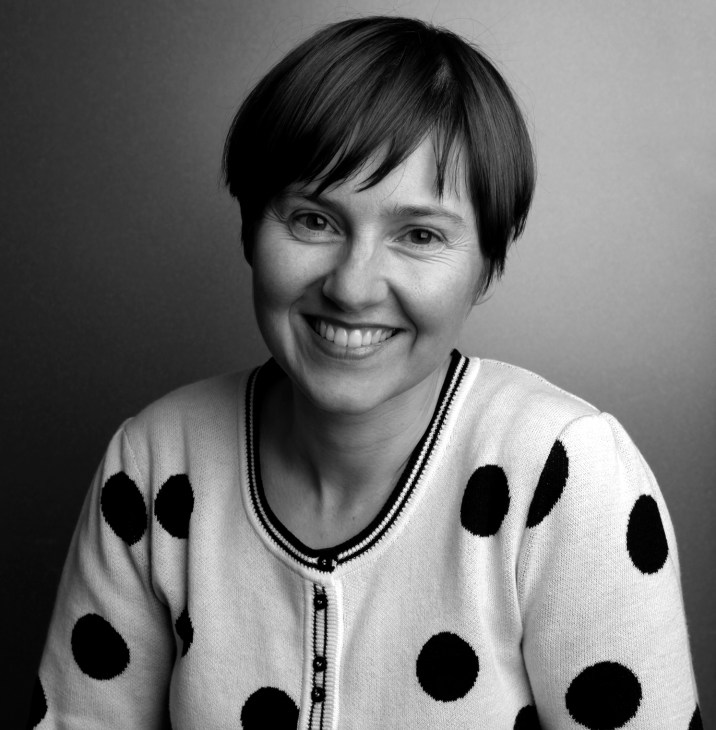Black and white portrait photograph of a woman with short dark hair wearing a polka dot cardigan.