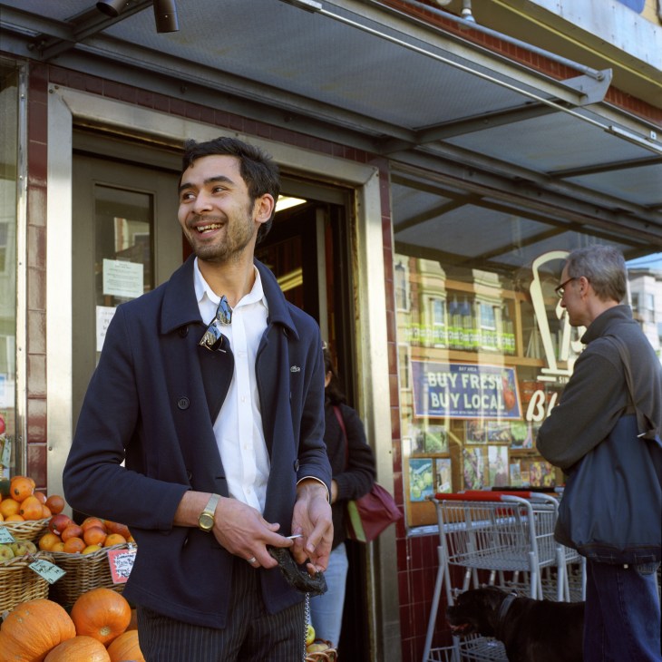 Man in navy blazer smiling outside Bi-Rite Market storefront with produce baskets and signage visible.