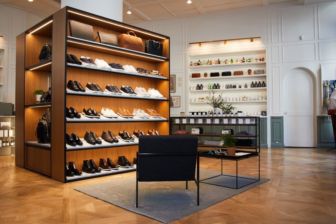 Want Apothecary retail interior with wooden shoe display shelving and skincare products on wall shelves.