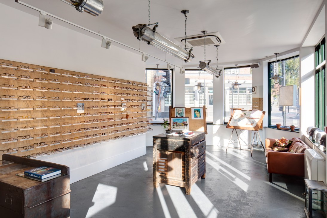 Interior of Cubitts optical store in King's Cross with wooden eyeglass displays and racing green accents.