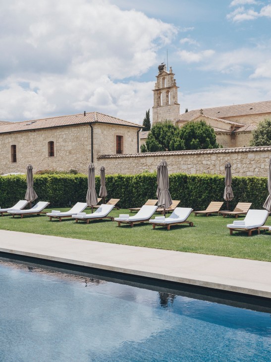 Outdoor swimming pool with lounge chairs in peaceful hotel grounds