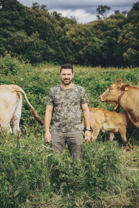 Cattle farmer Michel Rios standing in a field with his Galician blond cows in Dodro