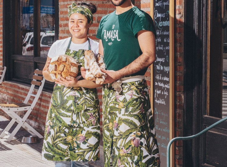 Reina and David of Amasa bakery standing outside their shop wearing matching tropical print aprons