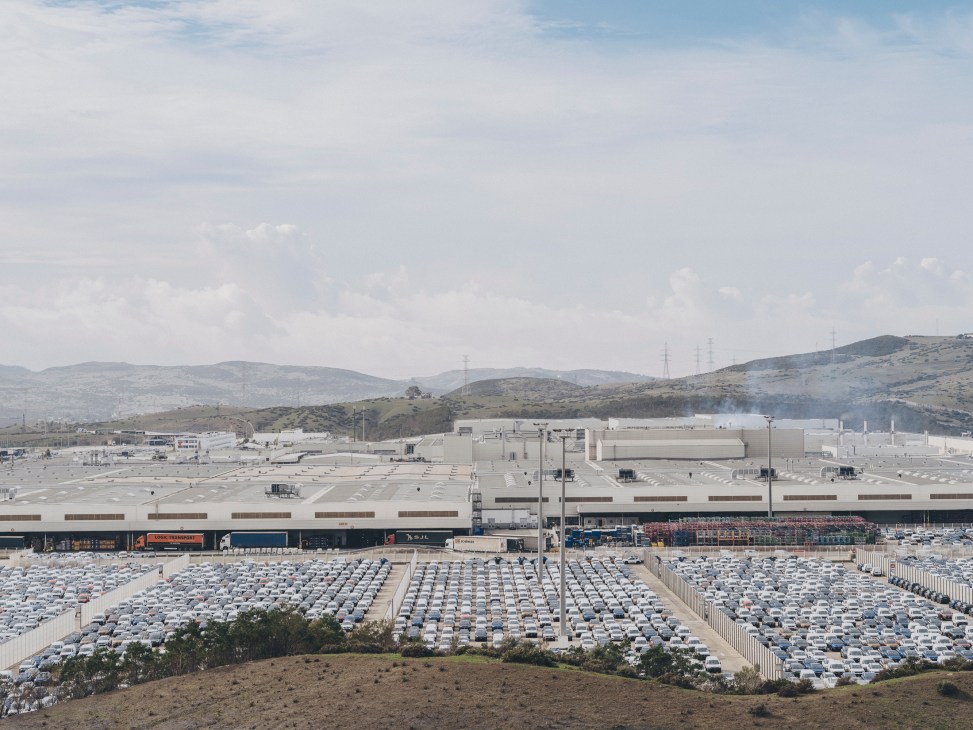 Aerial view of Renault car manufacturing plant with large parking lots filled with white vehicles in rows