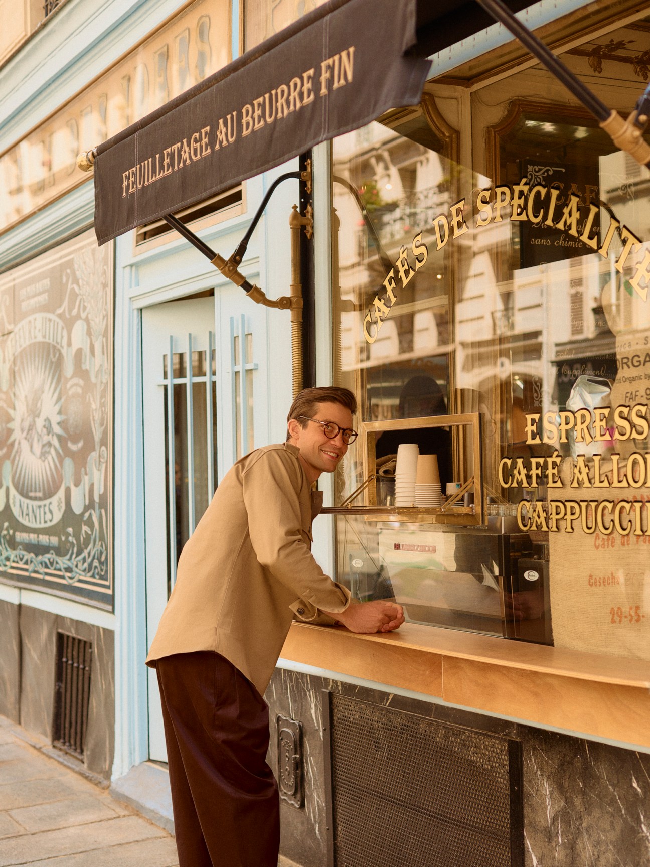 Man in beige shirt and glasses standing at French pastry shop window counter on Parisian street