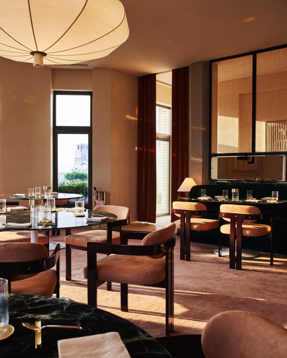 Elegant restaurant interior with warm lighting, round dining tables, upholstered chairs and large windows