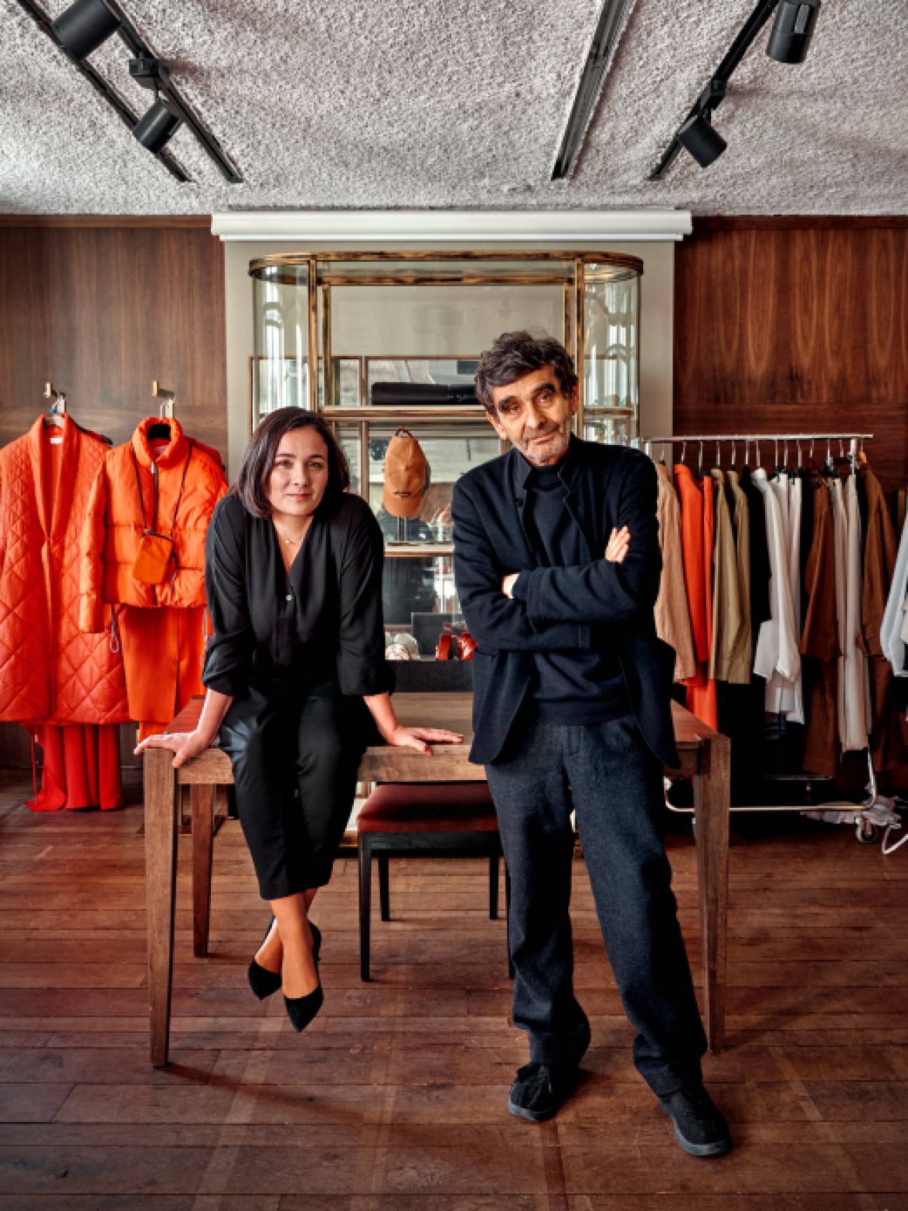 Adolfo and Adriana Domínguez sitting together in a fashion showroom with clothing displays