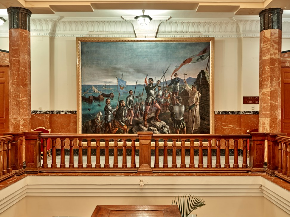 Large oil painting of Pedro de Estopiñán in ornate gold frame displayed in formal marble-columned government building
