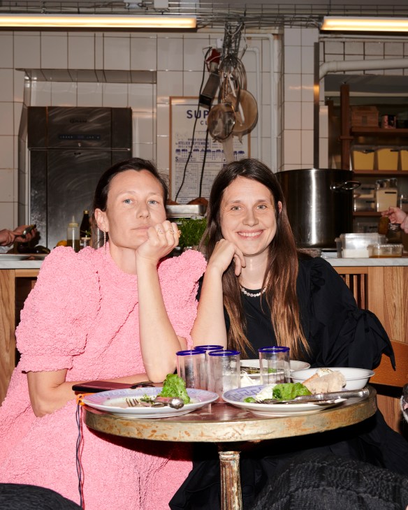 Two women sitting at a restaurant table having lunch with wine glasses and plates of food