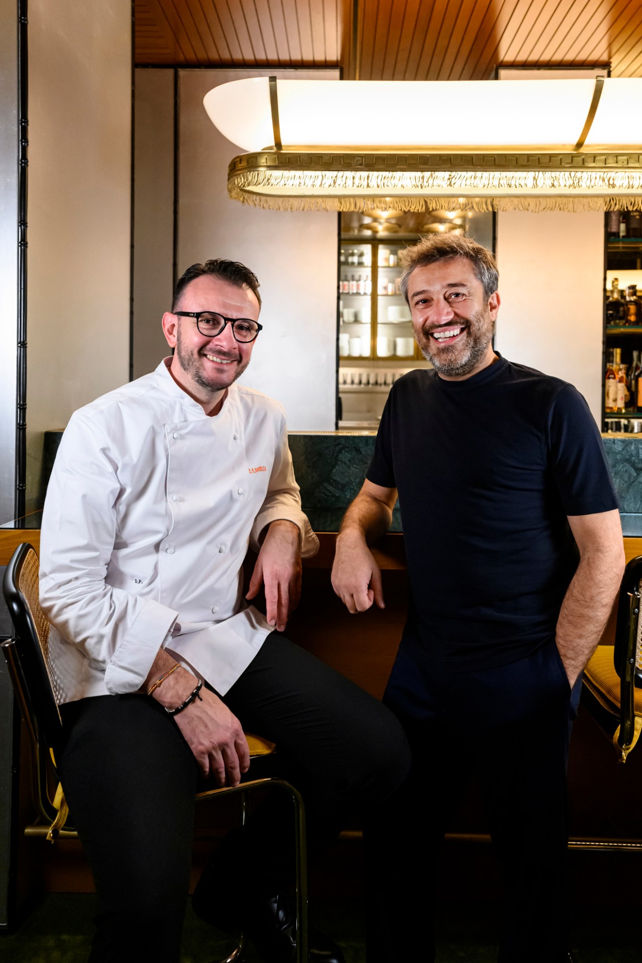 Chef Denis Pedron and Enrico Buonocore standing together in modern restaurant interior
