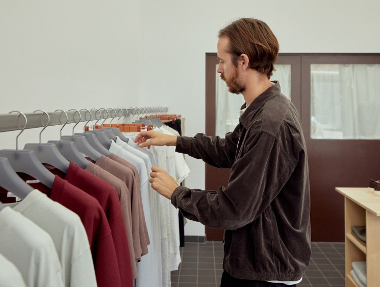Man browsing clothing on a rack inside a minimalist retail shop