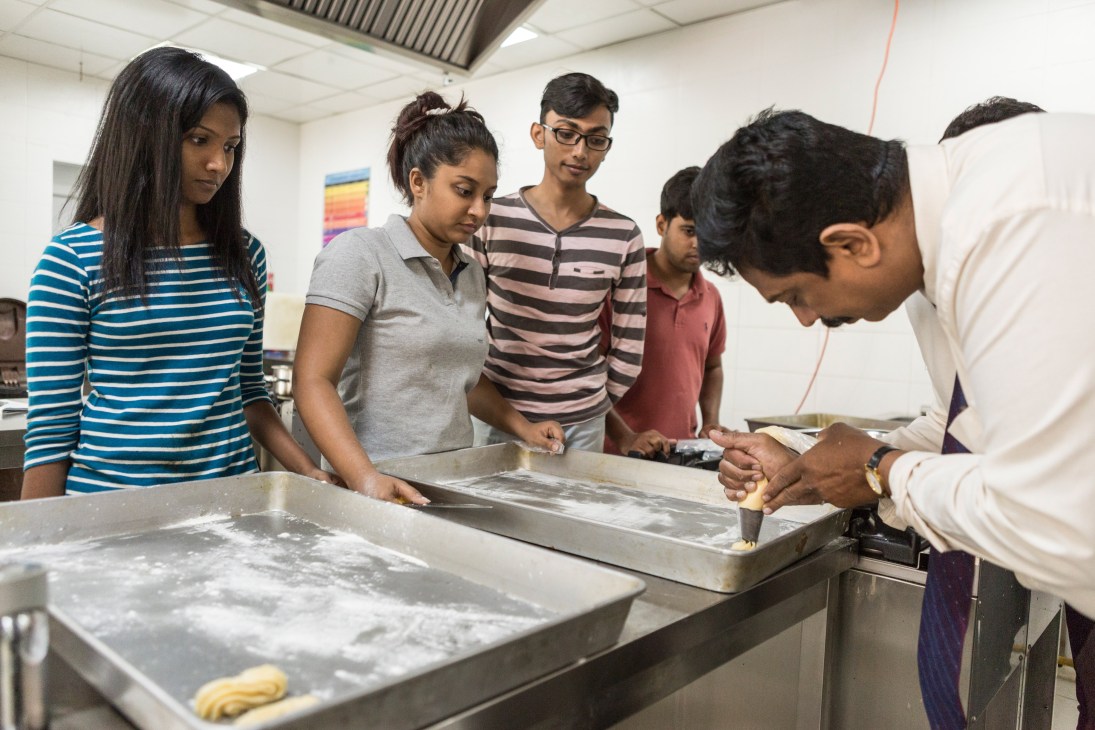 Students piping icing onto pastries during a culinary demonstration at the Colombo Academy of Hospitality.