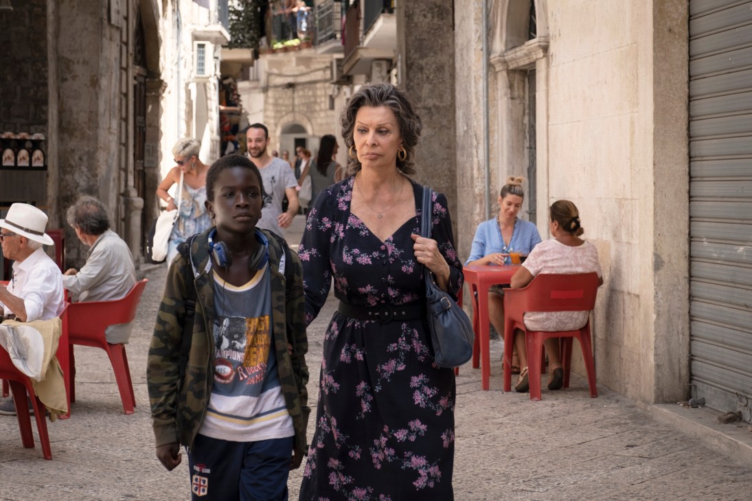 Still from The Life Ahead featuring Sophia Loren walking with a young boy on a cobblestone street