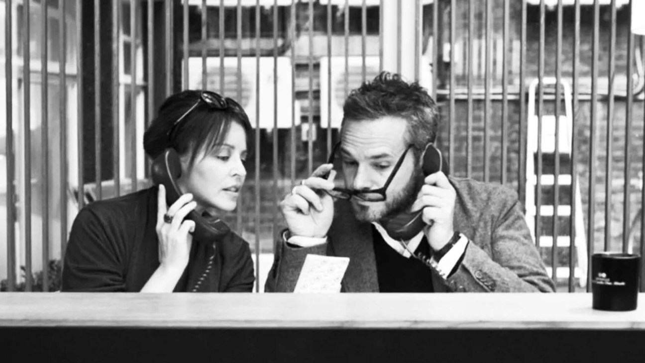 Two people on phones in what appears to be a radio studio or broadcasting environment