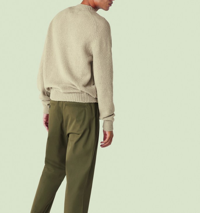 Model wearing De Bonne Facture × Monocle tawny wool knit sweater with mock neck and olive trousers.