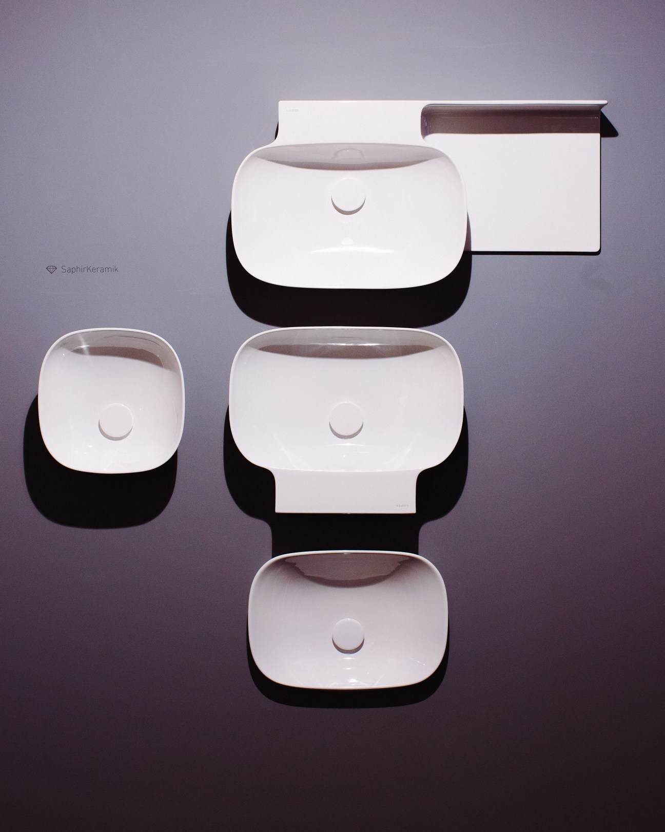 SaphirKeramic sinks by Laufen displayed in various sizes with white ceramic bowls and black bases.