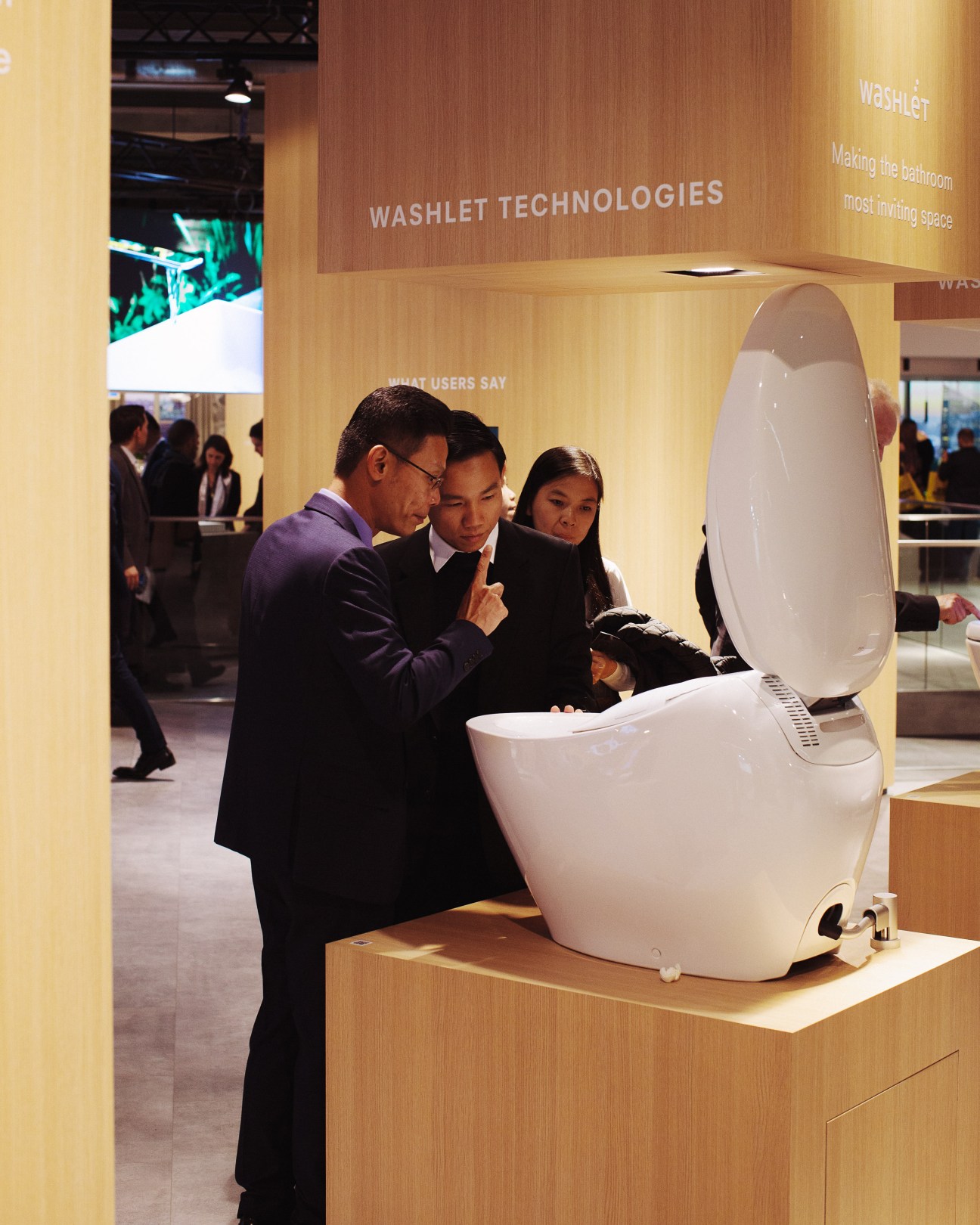 Visitors examine a white Toto toilet with an integrated lid at the Toto stand during ISH trade fair.