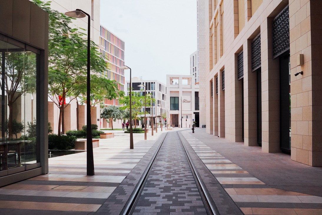 A modern urban street with tram tracks, trees, and contemporary buildings in Singapore.
