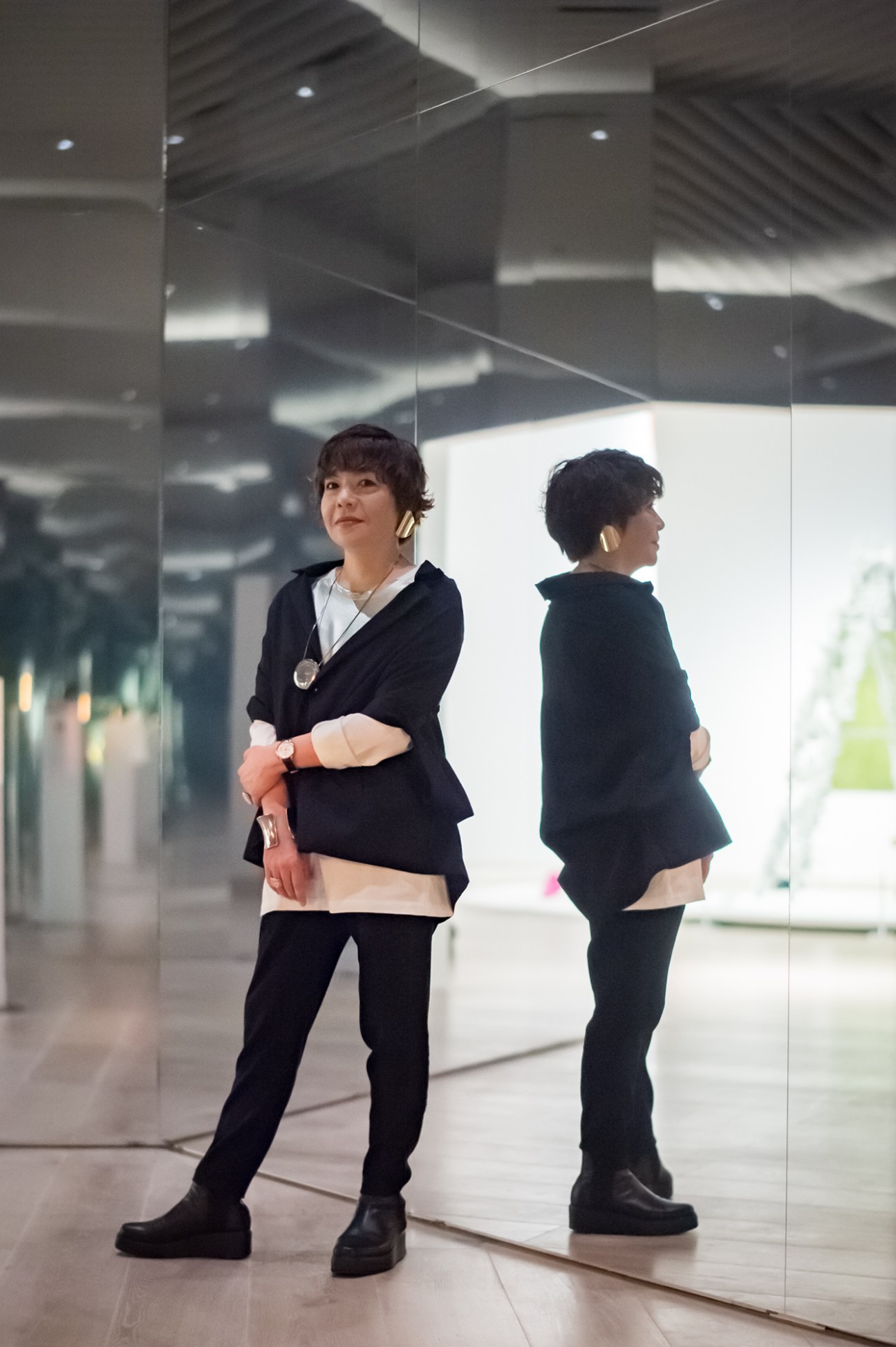 Mami Kataoka standing against mirrored surfaces in a modern interior space