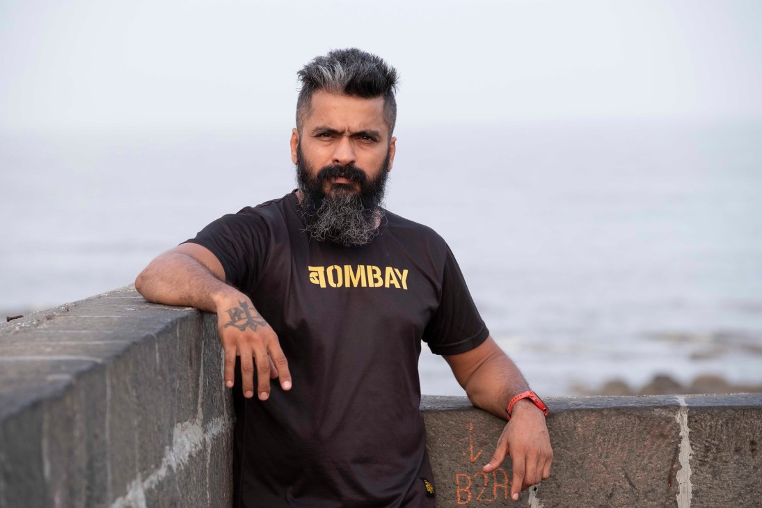 Deepak Oberoi, co-founder of Bombay Running, poses against a concrete barrier near the ocean in Mumbai