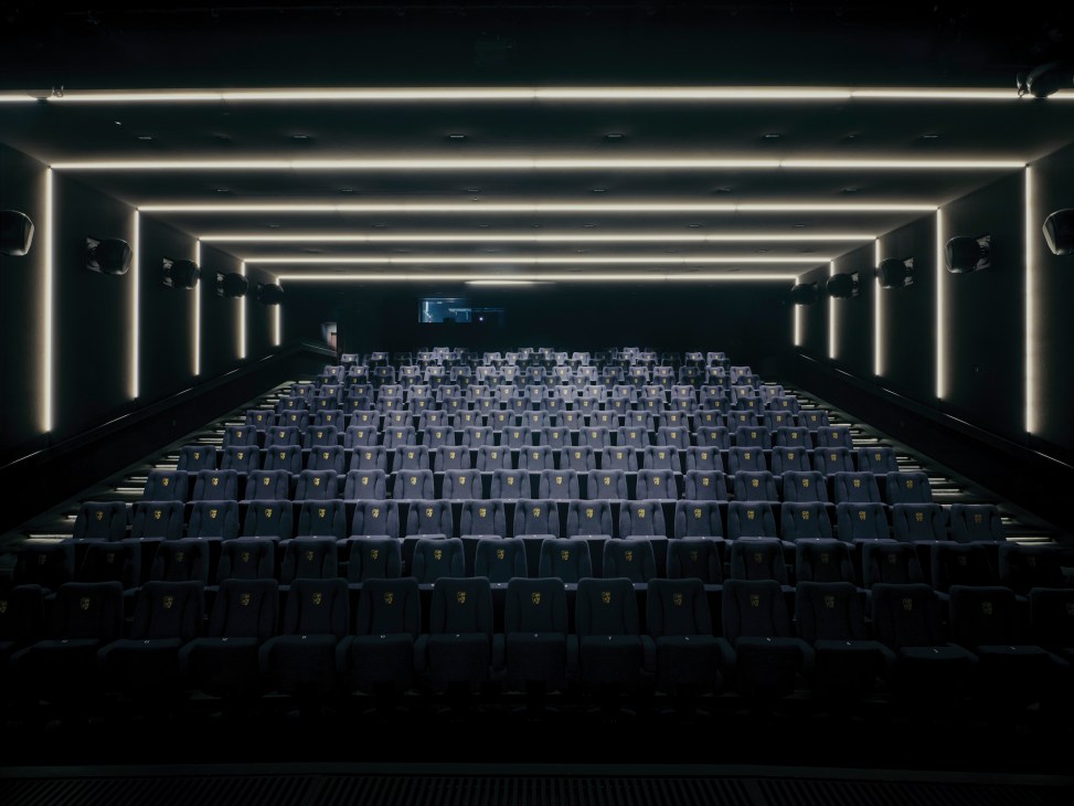 Modern cinema screening room with tiered blue velvet seats and geometric white LED lighting on ceiling and walls