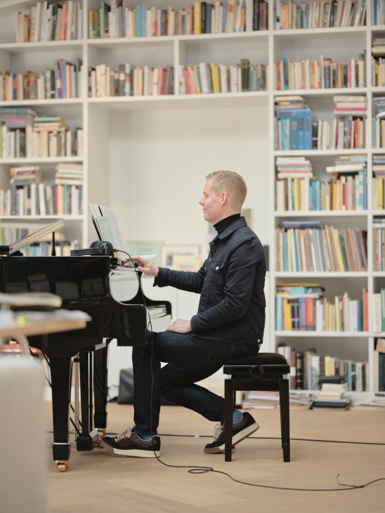 Composer Max Richter seated at his piano in his personal studio space