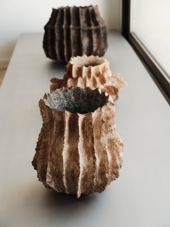 Ceramic vases by Berlin-based artist Jojo Corväia displayed on white shelves in boutique interior