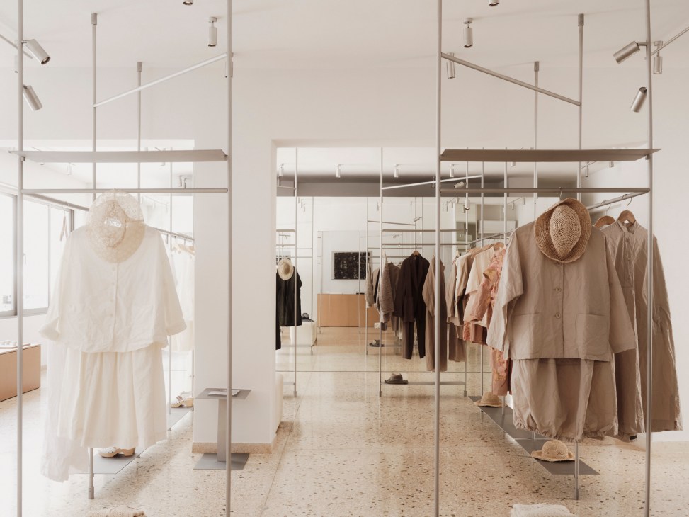 Minimalist boutique interior with clothing racks displaying neutral-toned garments and contemporary lighting fixtures