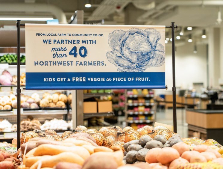 PCC Community Markets produce display with signage about partnering with Northwest farmers and offering free vegetables to children.