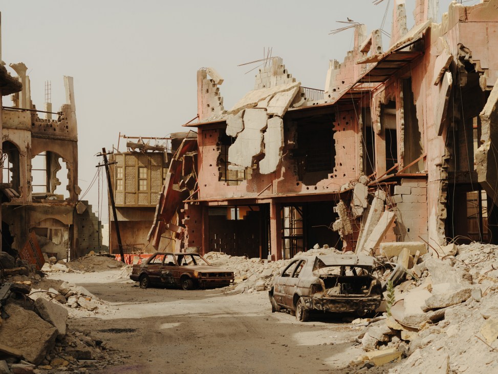 War-torn city film set with destroyed buildings, damaged vehicles, and rubble in UAE desert.