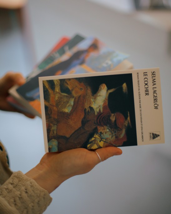 Hand holding Swedish book 'Selma Lagerlöf' by Le Cocher with artistic cover showing figures in earth tones