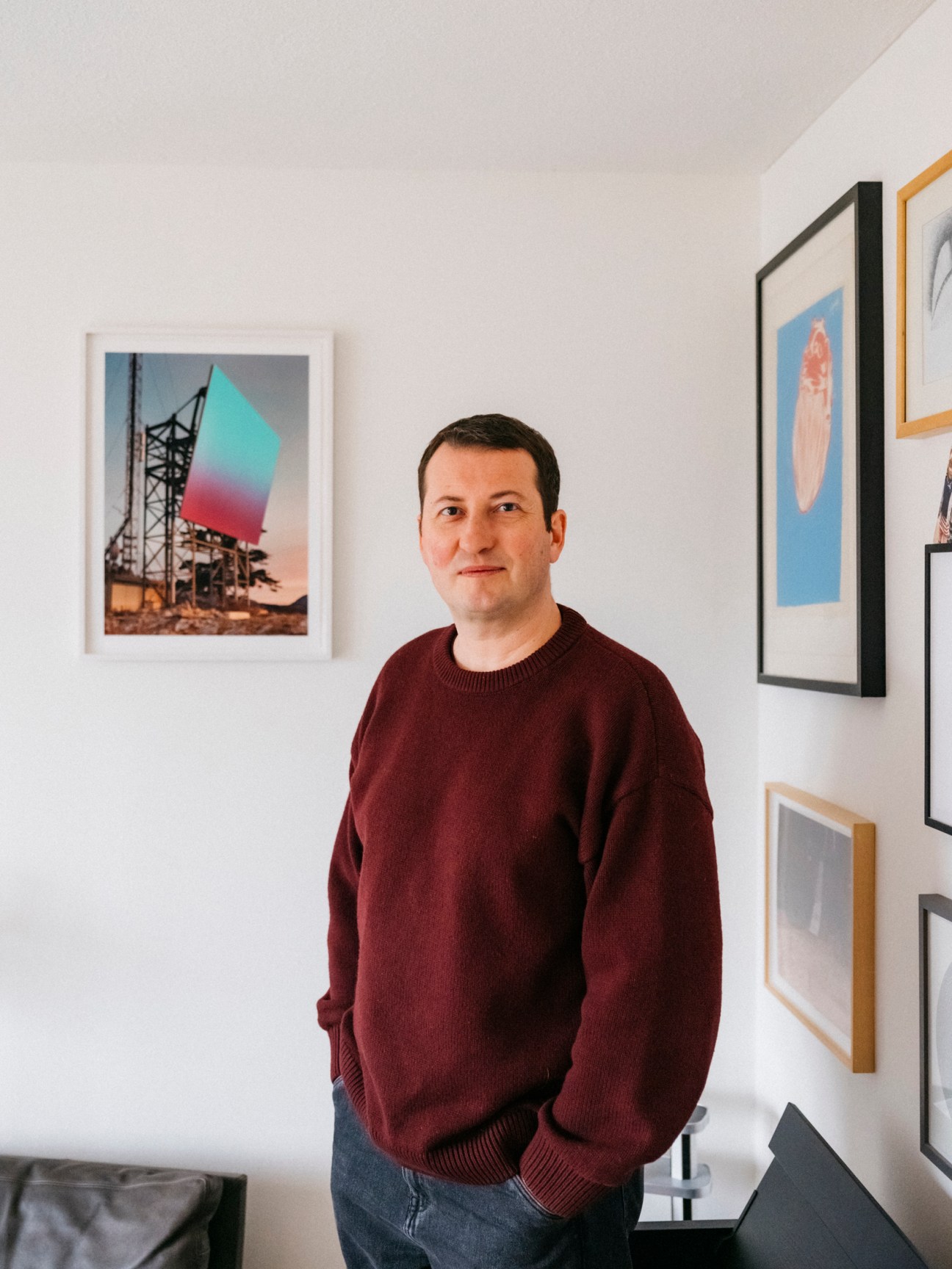 a portrait of a man in front of walls covered with artwork
