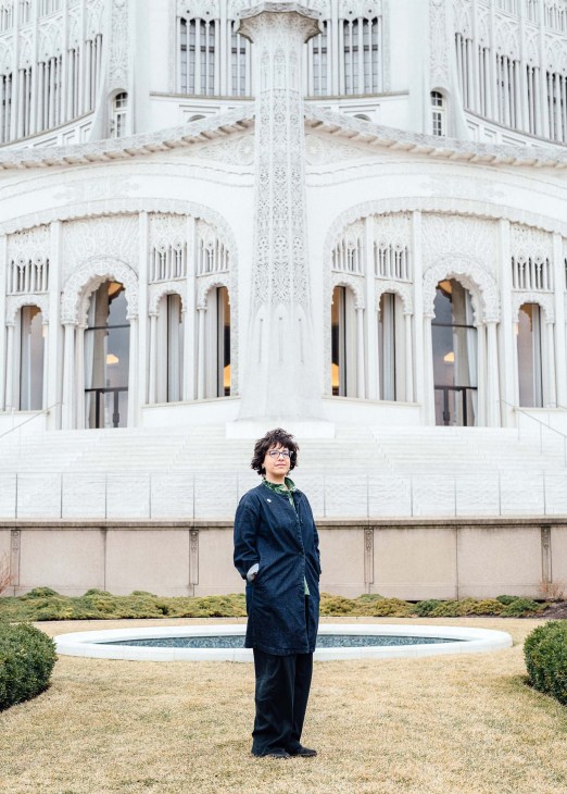 Jennifer Brandel stands in front of the Bahá'í House of Worship in Chicago, wearing a dark blue coat and glasses.