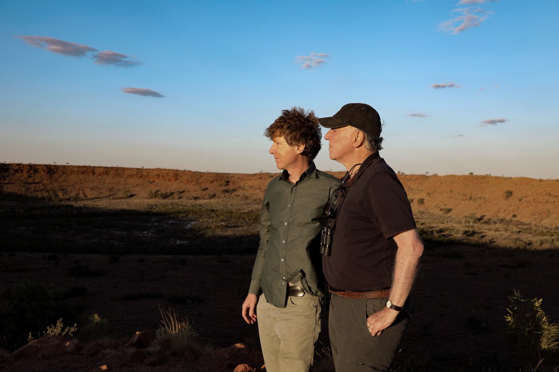 Two men standing in an arid landscape at dusk or dawn with dramatic sky