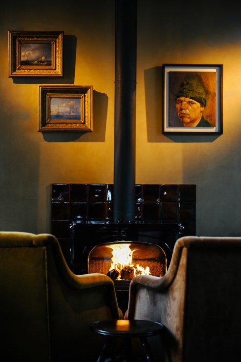 Cozy fireplace seating area with framed paintings on yellow walls and modern chairs