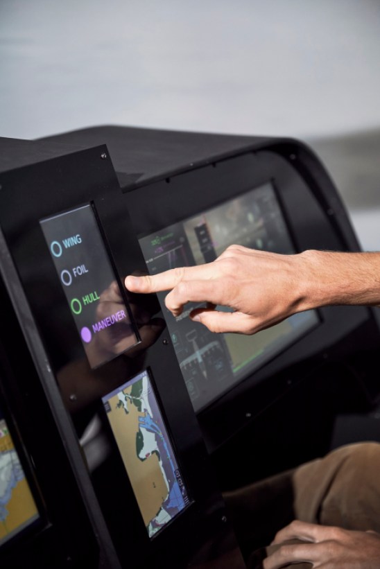 Hand touching touchscreen controls showing Wing, Foil, Hull, and Maneuver options in Regent's sea glider cockpit simulator