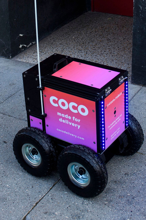 Pink Coco delivery robot with four wheels on sidewalk pavement