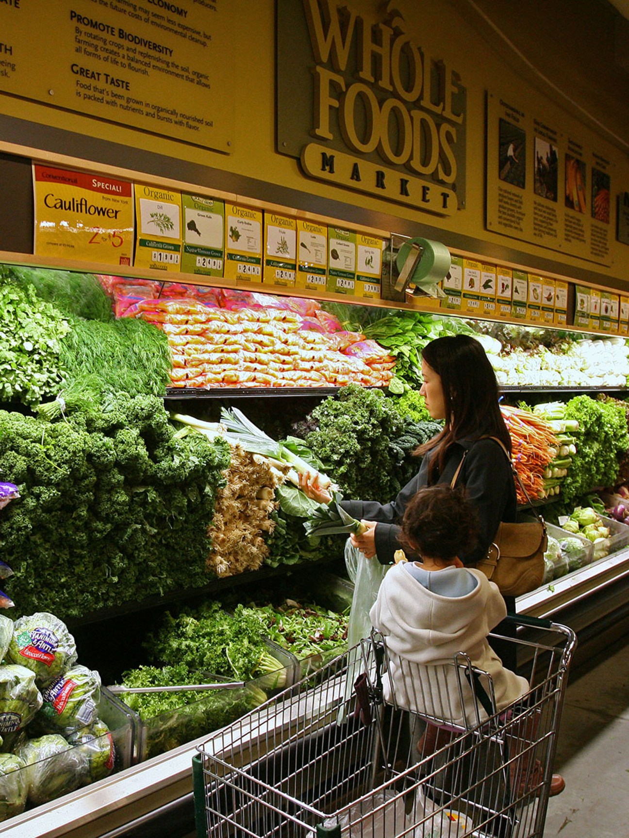 Wholefoods mother and child in trolley shopping fresh produce