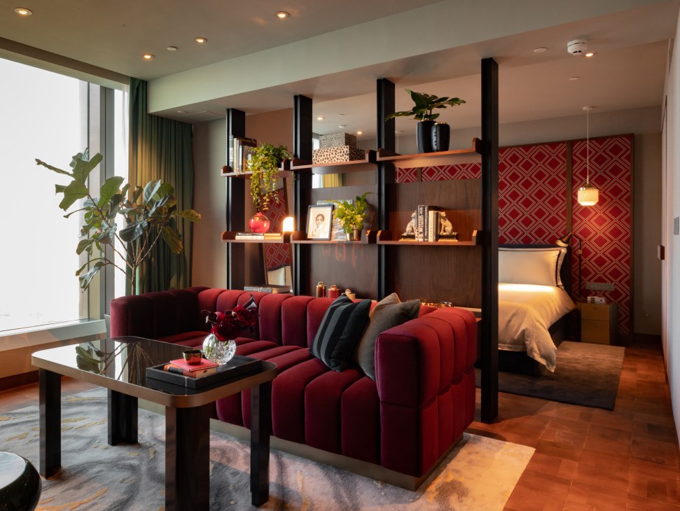 Modern bedroom with burgundy tufted sofa, black shelving unit, and bed with red geometric patterned headboard