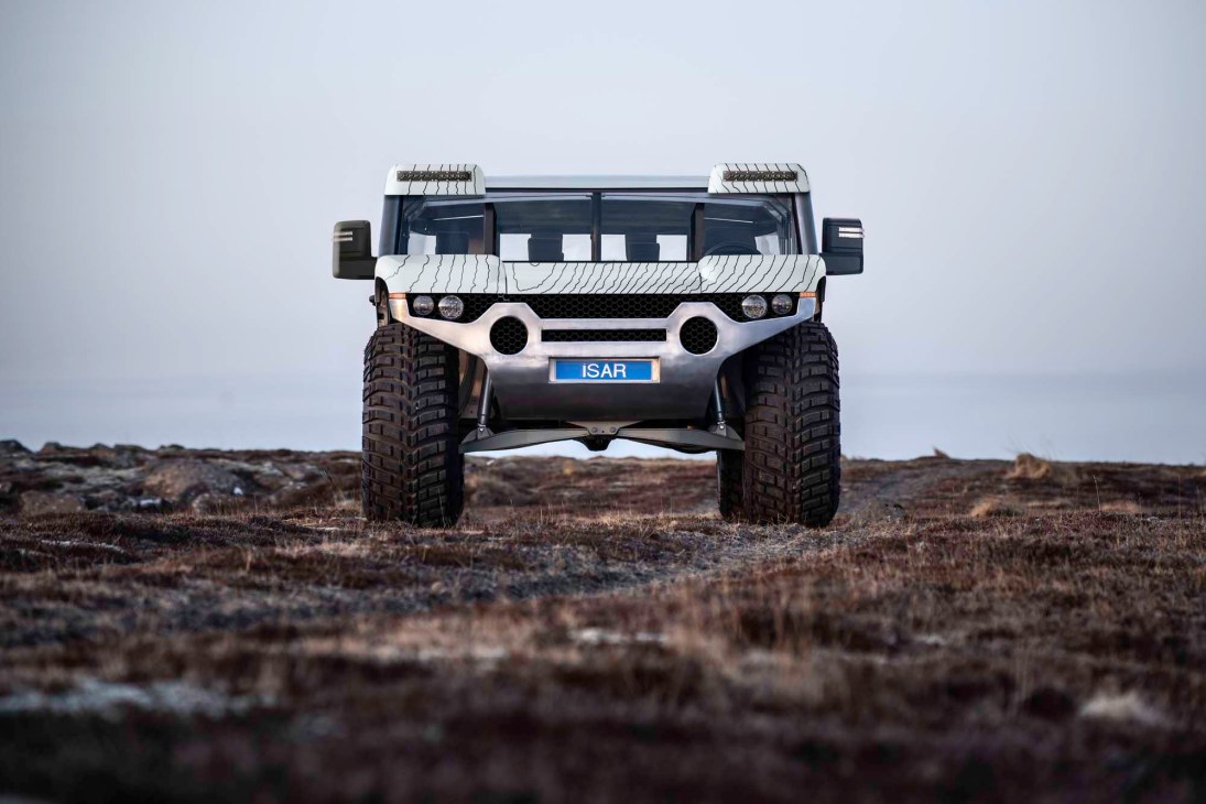 White ISAR autonomous off-road vehicle with large tires on rocky terrain against overcast sky