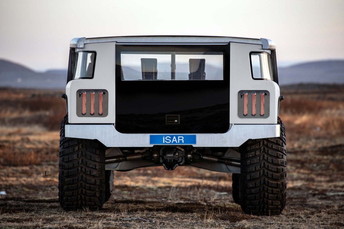 Rear view of white ISAR electric off-road vehicle prototype with distinctive taillights in desert landscape