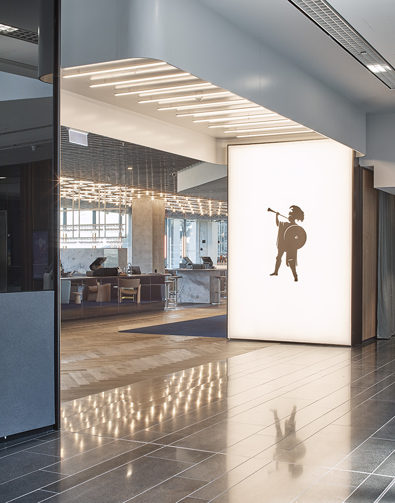 Modern restaurant or hotel entrance featuring sleek architecture with illuminated ceiling and silhouette figure on wall