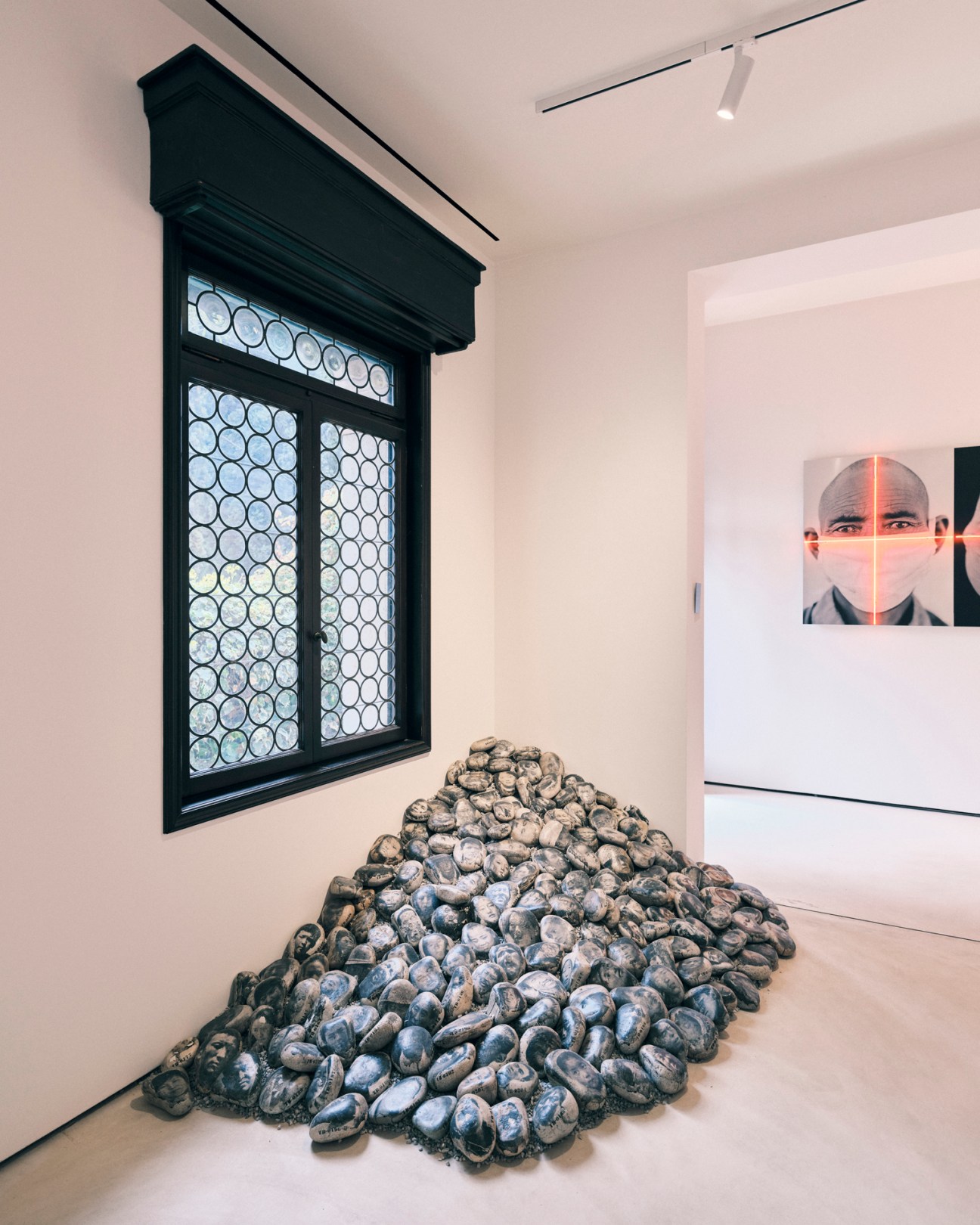 Gallery installation with framed window display of coins and pile of sculptural vessels on white floor