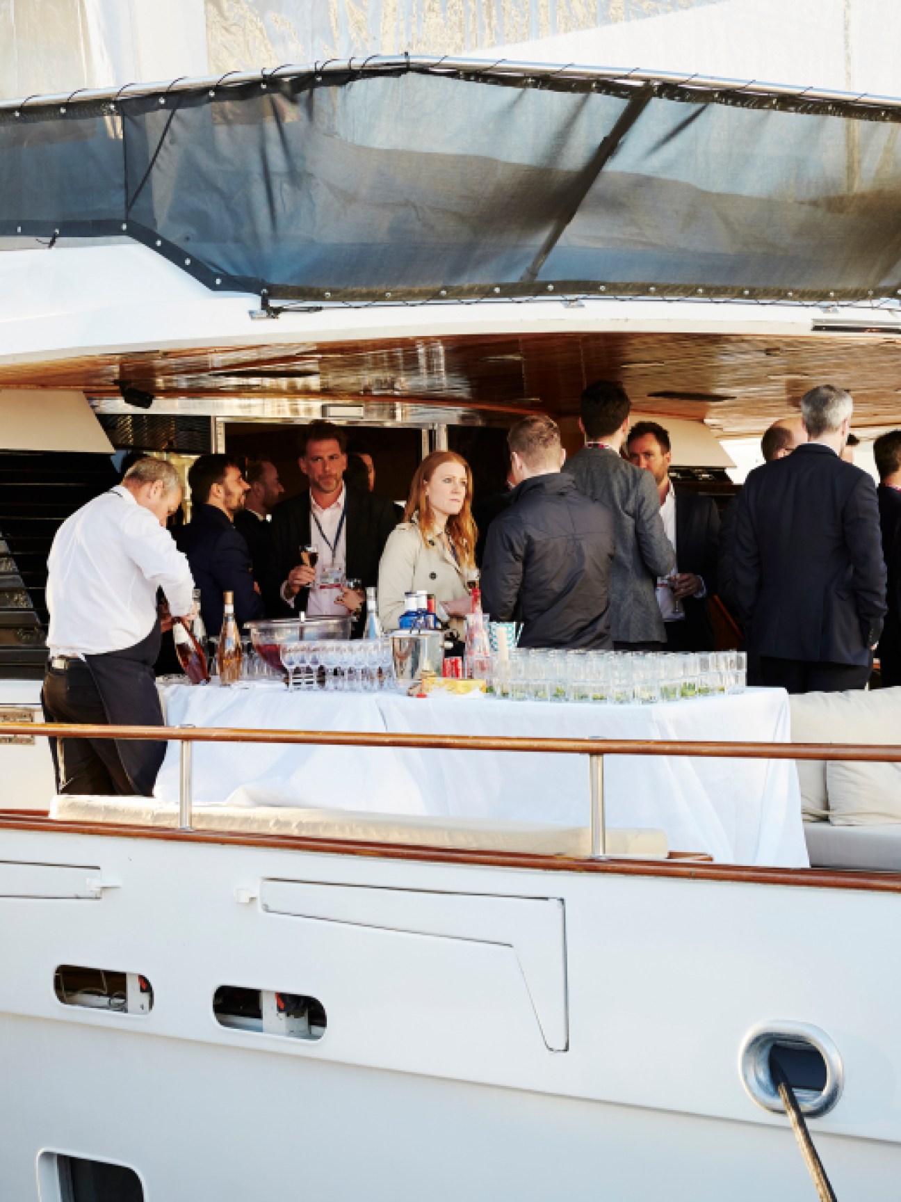 Business professionals in formal attire networking and socializing on the deck of a luxury yacht during Mipim