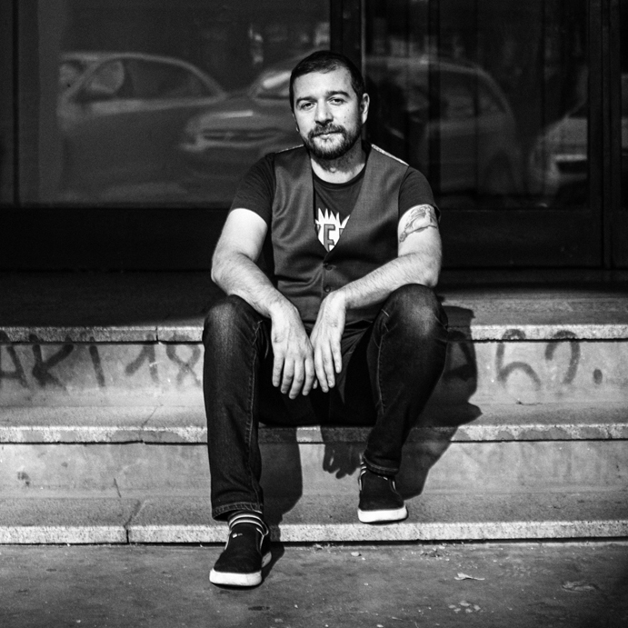 Portrait of Stevan Dojcinovic sitting on stone steps in black and white