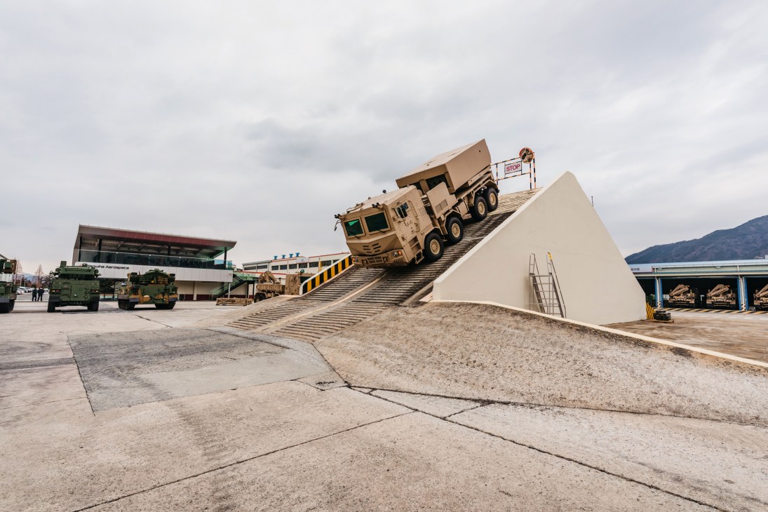 Military vehicle climbing steep incline during testing at Hanwha facility