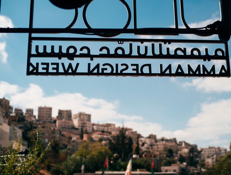 Amman Design Week sign framing a hillside cityscape view.