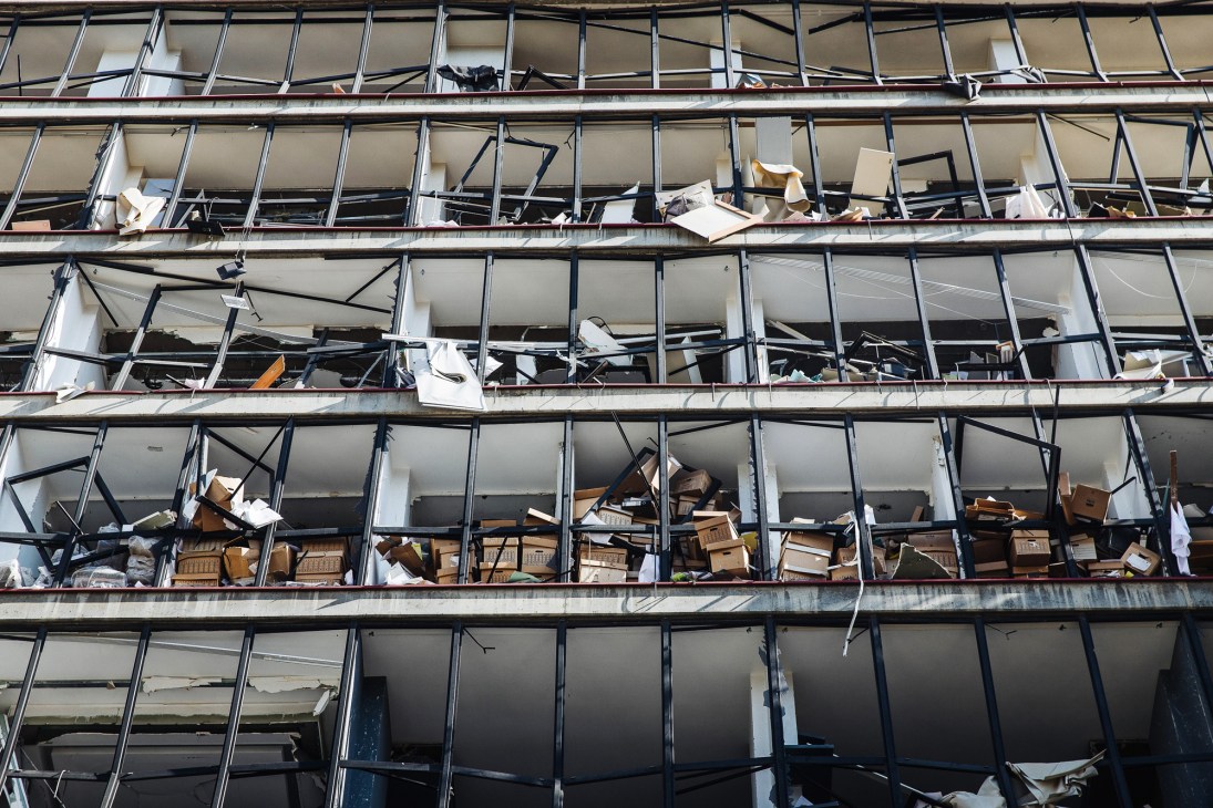Damaged office building with shattered windows and debris scattered across multiple floors after explosion