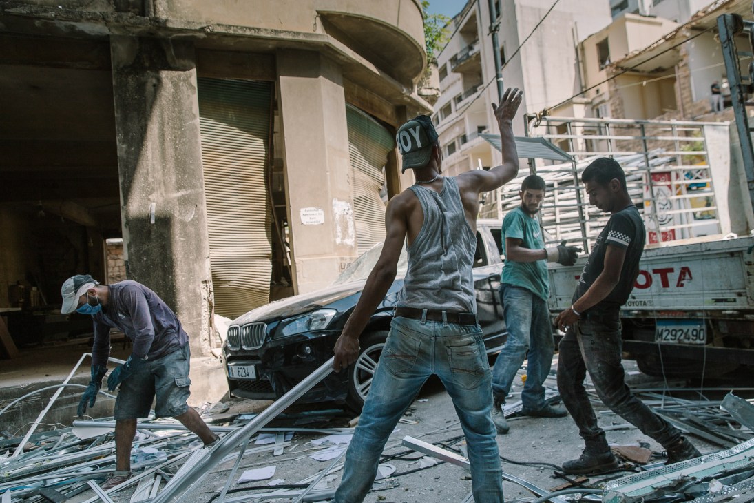 Young volunteers with brooms and cleaning equipment working to clear glass and debris from destroyed streets