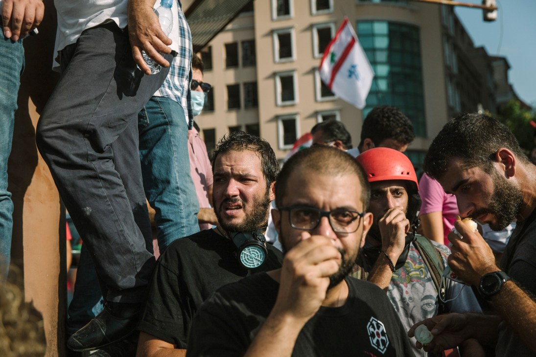 Crowd of protesters gathering in downtown Beirut holding Lebanese flags and banners demanding government accountability